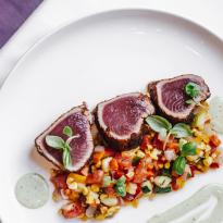 Three medallions of seared tuna, plated with a relish of fresh corn, tomatoes, and cucumbers
